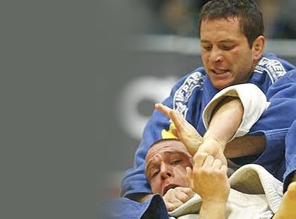 Tiago Camilo de kimono azul dando golpe em judoca